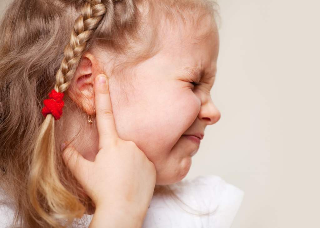 mała dziewczynka wskazująca palcem na bolące ucho
