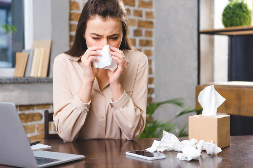 kobieta zmagająca się z alergią na kurz wyciera nos za pomocą chusteczek